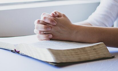 Hände über Bibel gefaltet